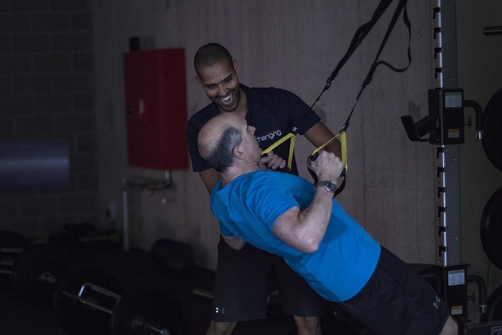 Un coach Body Life Changing accompagne un membre sur un exercice en suspension